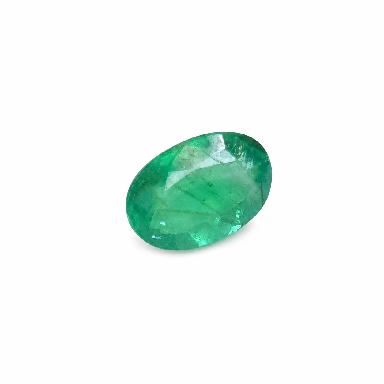Loose 0.72 carat oval Colombian emerald displaying vivid green colour and naturally occurring internal inclusions.