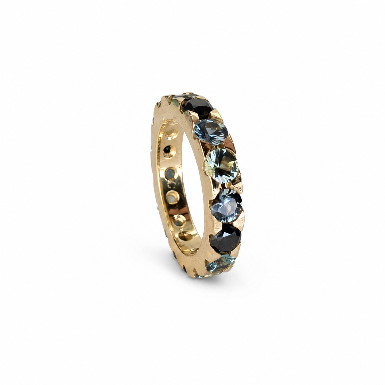 Handmade full eternity band featuring round teal sapphires and black diamonds set continuously in 14K yellow gold