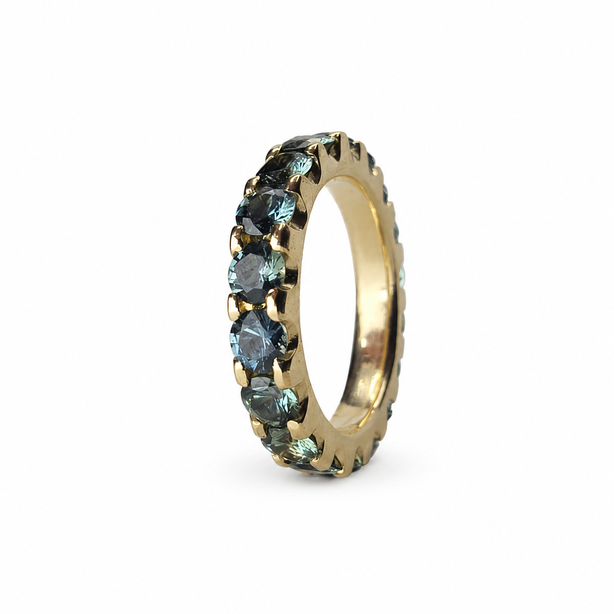 Full eternity band featuring 3.60 carats of round Madagascar teal sapphires set continuously in 14K yellow gold.