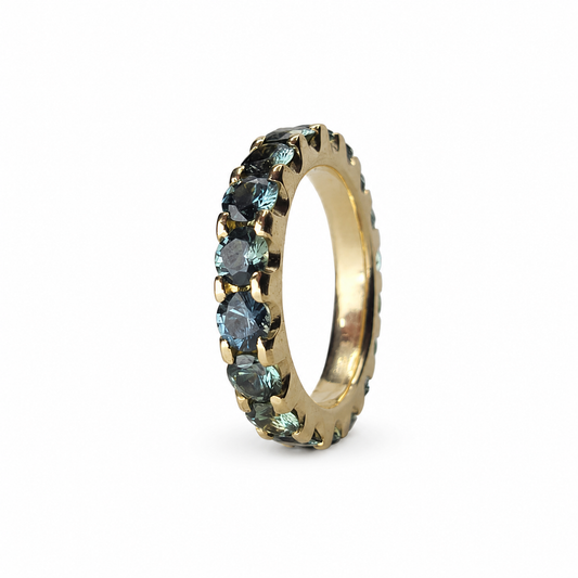 Full eternity band featuring 3.60 carats of round Madagascar teal sapphires set continuously in 14K yellow gold.