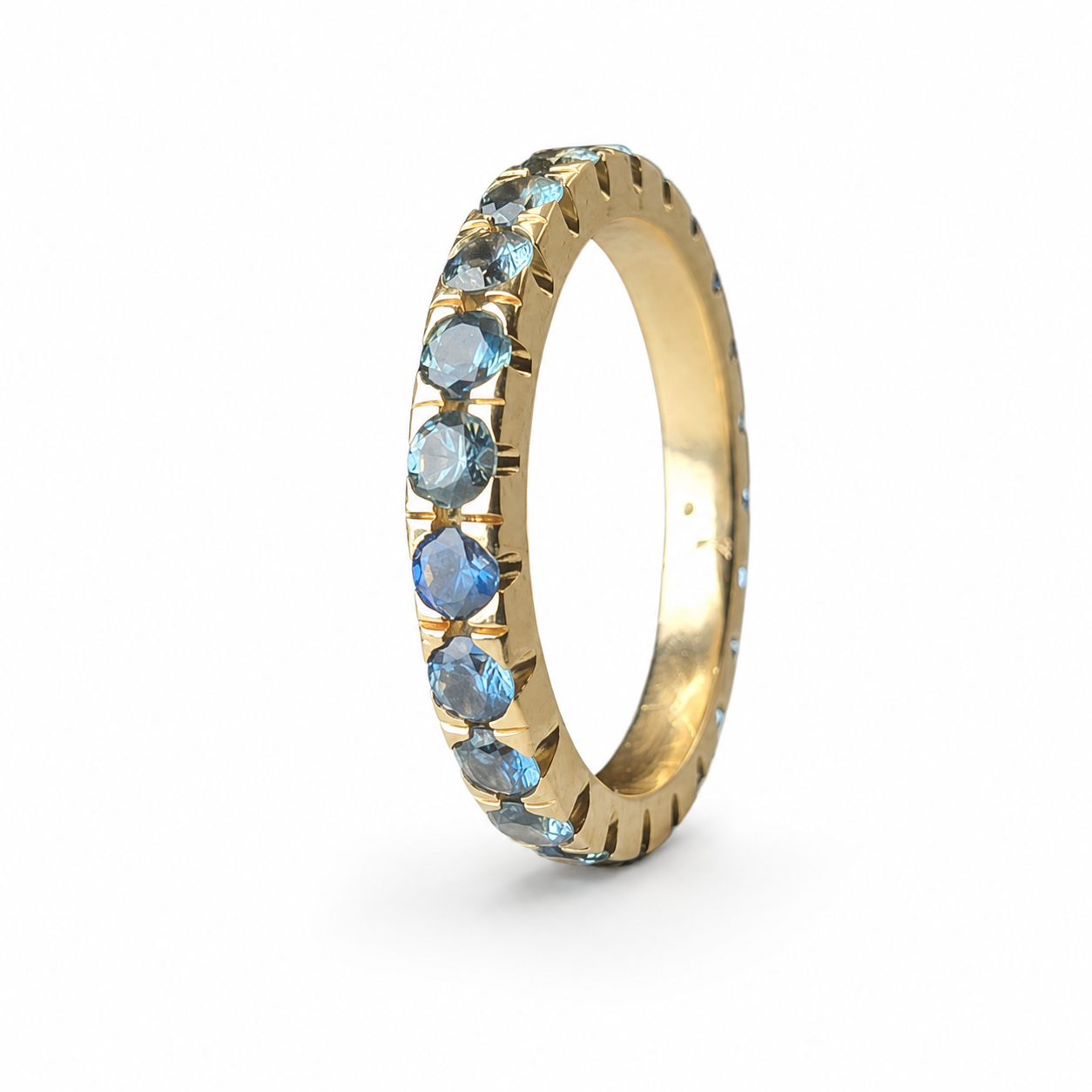 Handmade 14K yellow gold eternity band featuring 2.30 carats of blue Montana sapphires arranged in a continuous colour gradient.