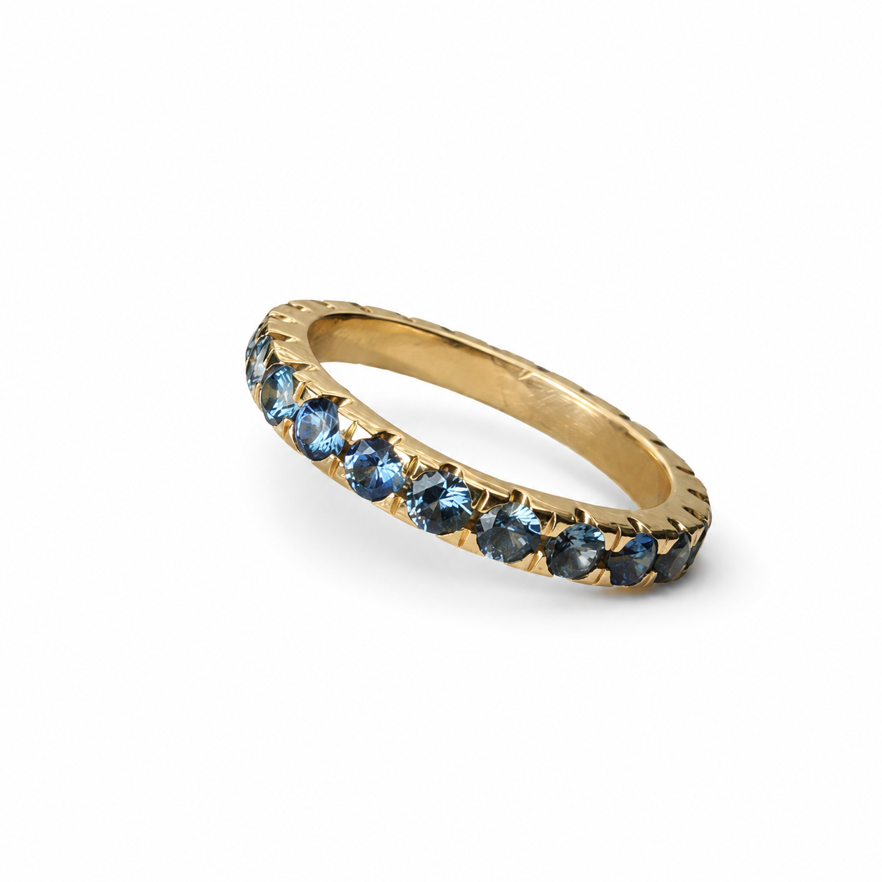 Handmade 14K yellow gold eternity band featuring 2.30 carats of blue Montana sapphires arranged in a continuous colour gradient.
